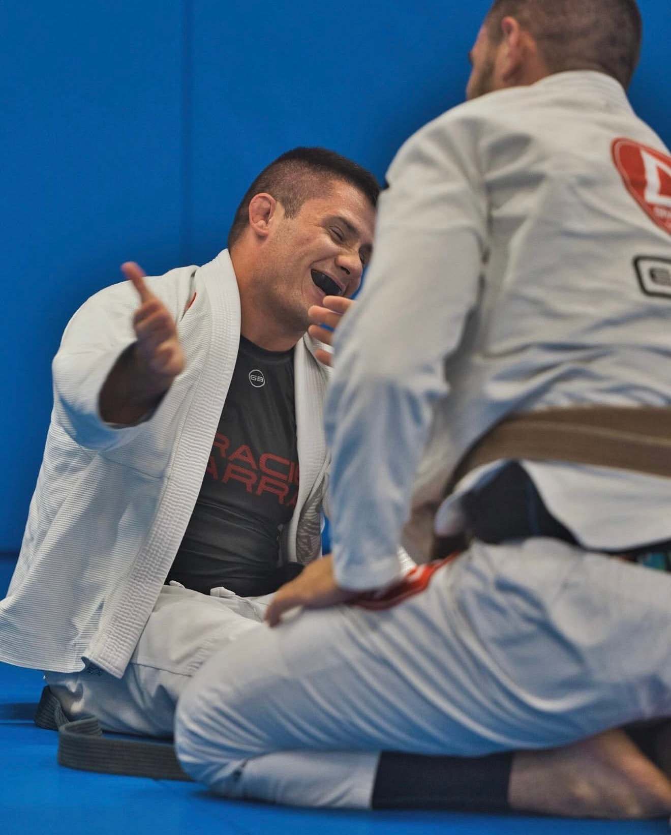 Two training partners in white gis share a laugh between rounds on the mat